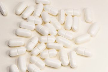 White pills scattered on a white background close-up