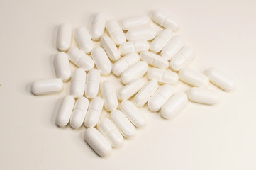 White pills scattered on a white background close-up