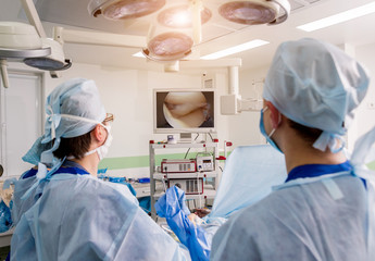 Arthroscope surgery. Orthopedic surgeons in teamwork in the operating room with modern arthroscopic tools. Knee surgery.