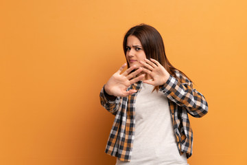 Young woman over brown wall nervous stretching hands to the front