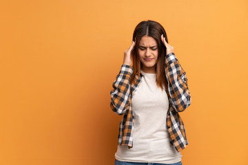 Young woman over brown wall with headache