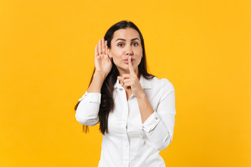 Portrait of beautiful young woman in white shirt say hush be quiet with finger on lips shhh gesture...