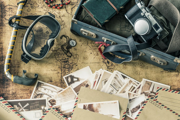 retro mask and snorkel with a suitcase, notebook, old map, souvenir cards and travel equipment / holiday concept