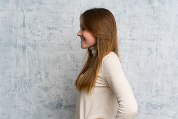 Young woman over grunge wall standing and looking to the side