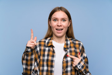 Young woman over blue wall with surprise facial expression