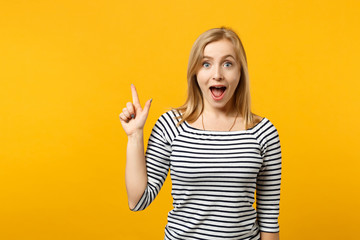 Excited young woman in striped clothes keeping mouth open hold index finger up with great new idea isolated on yellow orange background. People sincere emotions, lifestyle concept. Mock up copy space.