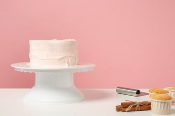 Fototapeta na wymiar Chef cook confectioner baker white table isolated on pink pastel background in studio. Nude cake with sweet rose cream without decoration, cinnamon cupcake. Mock up copy space food concept. Nobody.