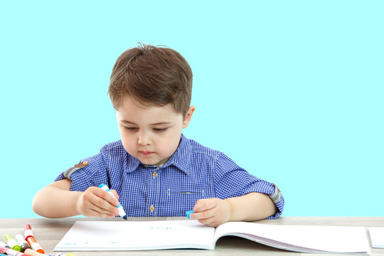 little boy sits and draws writes on an isolated background