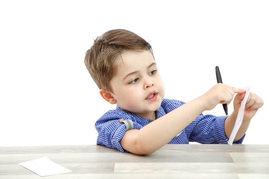 a little boy of preschool age shows a paper on which he wrote or painted something