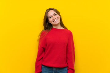 Young woman over yellow wall smiling