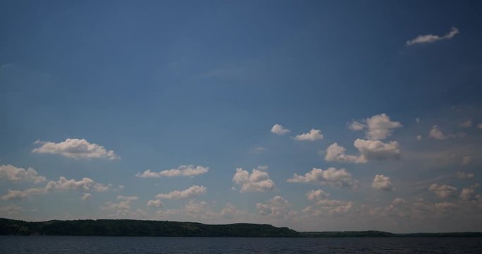 Time lapse. Intensive formation of comulus clouds  in hot day above huge river. 4K.