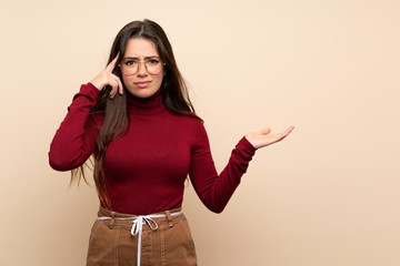 Teenager girl with glasses making the gesture of madness putting finger on the head