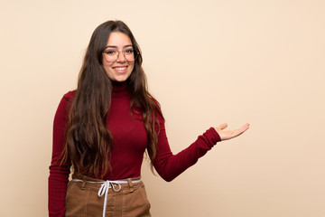 Teenager girl with glasses presenting an idea while looking smiling towards