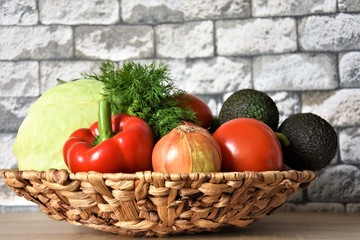 fresh vegetables, white cabbage ,, red wig, tomatoes, avocado and onion in a wicker natural vase