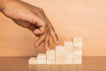Hand liken business person stepping up a wooden toy staircase on wooden textured background