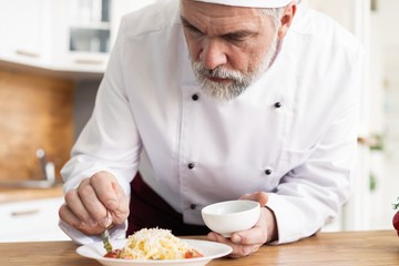Chef grates cheese to the plate with fresh pasta.