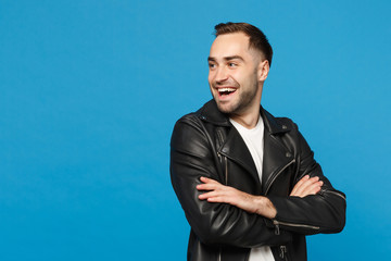 Handsome stylish young bearded man in black leather jacket white t-shirt looking aside isolated on blue wall background studio portrait. People sincere emotions lifestyle concept. Mock up copy space.