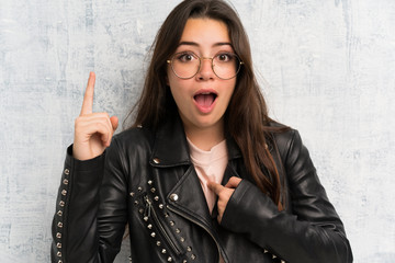 Teenager girl over grunge wall with surprise facial expression