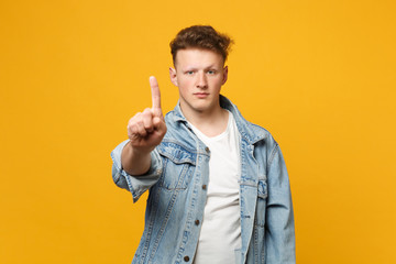 Handsome young man touch something like push click on button, pointing at floating virtual screen isolated on yellow orange background. People sincere emotions, lifestyle concept. Mock up copy space.