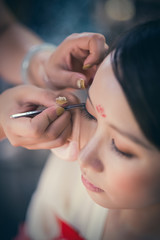 Obraz premium A Chinese woman is doing makeup before a traditional opera show.