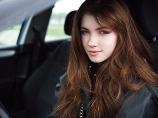 Plakat Close up portrait of young attractive red hair self-employed business woman driver sitting in white car stuck in a city traffic jam staring into camera running late to work noonday bleached colors