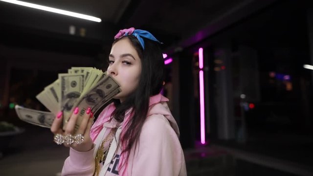 Rich girl play with dollars money at night city