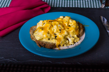 Scrambled eggs topped by grated cheese, with charcoal salt and red napkin