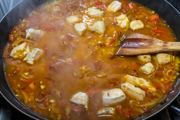 Cooking chicken paella with wooden spatula