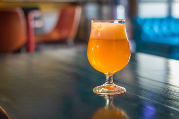 a glass of bright craft beer is on the table in the bar