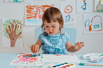 little girl holding a drawing lesson in the room at the table.