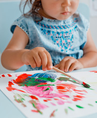 little girl holding a drawing lesson in the room at the table.