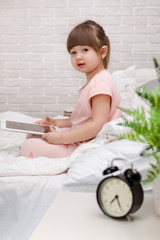 cute little child girl lies in bed uses digital tablet. child playing on tablet pc.