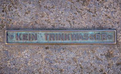 Kein Trinkwasser, Ein altes Eisenschild mit der Aufschrift kein Trinkwasser auf einem Hintergrund aus Stein.