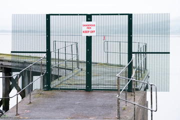 Fototapeta na wymiar Dangerous pier keep off sign on abandoned sea jetty