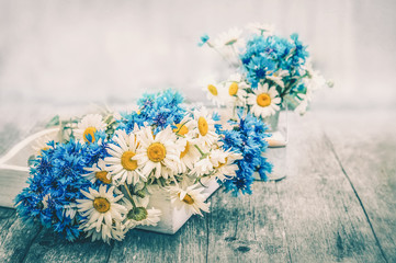 Bouquets of beautiful wild flowers of daisies and cornflowers on a wooden old background.