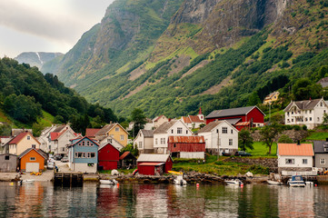Fototapeta na wymiar Small houses of the commune on the fjord, photographed from a sightseeing cruise ferry departing in summer from Flam, Norway