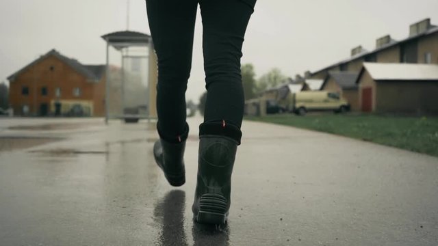 Tracking female in focus walking on wet surface with reflection of buildings. Steadicam slow motion footage.