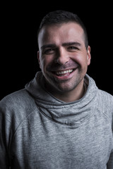 Fototapeta premium Studio portrait of a smiling man looking at the camera. Isolated on black background. Vertical.