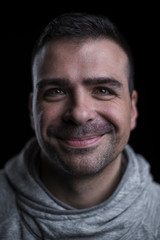 Studio close up portrait of a smiling man looking at the camera. Isolated on black background. Vertical. Selective focus.
