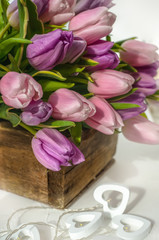 Beautiful garland of white hearts on a background of pink tulips. Congratulation.