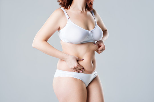 Woman with fat flabby belly, overweight female body on gray background