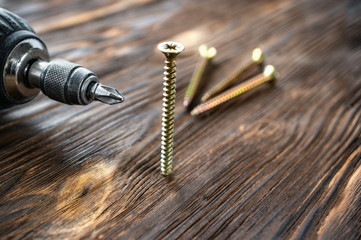 Manual screwdriver screws and dowels on a wood background