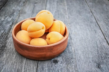 Naklejka na ściany i meble Ripe Golden apricots in wooden bowl on wooden background. Copy space
