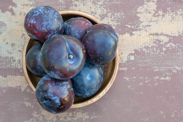 Harvest plums in a wooden dish on a wooden rustic background. Copy space. The view from the top