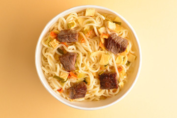 Paper cup with instant ramen noodles with beef and vegetables.