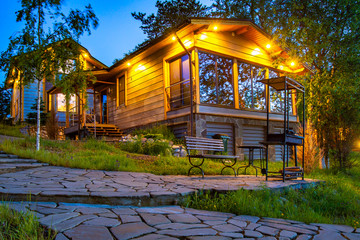 Evening illuminated cottage in Karelia. Country house with barbecue area. Karelian holiday resort....