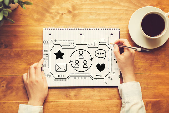 Social media with a person writing in a notebook on a wooden table