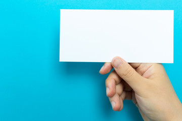 Hand holding up a note card on a blue background