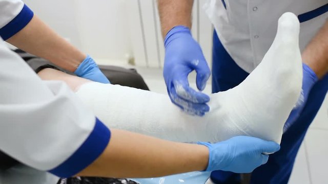 Doctor Traumatologist Puts A Plaster Or Cast On The Broken Leg Of The Patient.