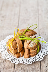 Fototapeta premium Fresh Italian cookies cantuccini with almonds stacked on white plate on ructic wooden table background.